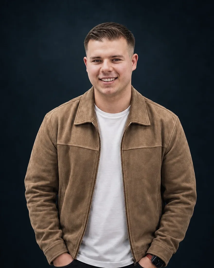 Patrik Schäfer smiling in a dark studio, wearing a light suede jacket